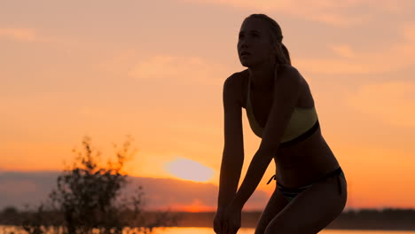 Schönes-Volleyballmädchen-Im-Bikini-Bei-Sonnenuntergang,-Unterarmpass-Mit-Ihrer-Teamkollegin-Während-Eines-Spiels